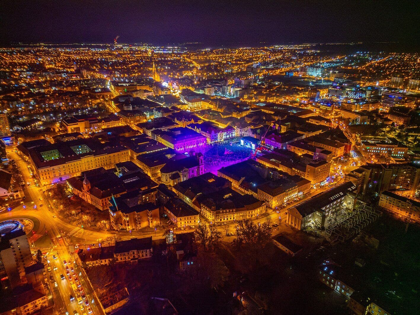 Centrul Timișoarei noaptea, văzut de sus, cu o piață luminată în violet