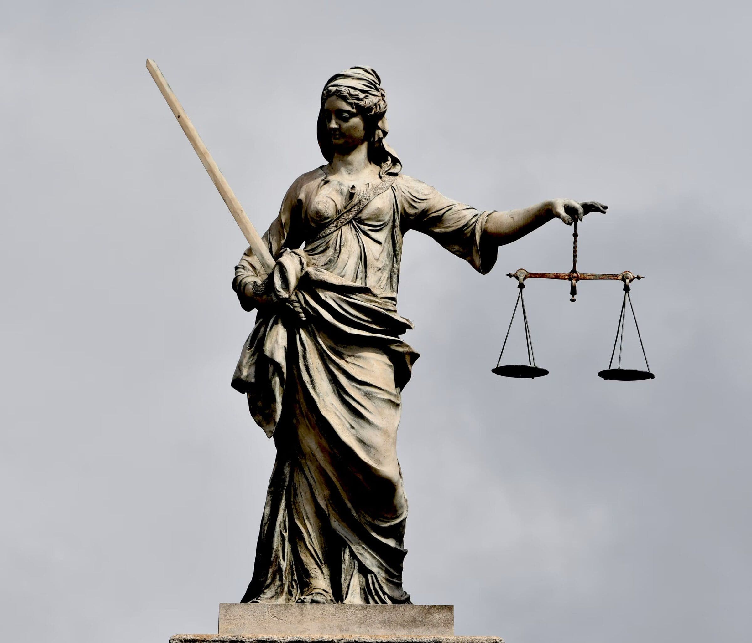 Statuie a Justiției cu balanța, pe cer înnorat