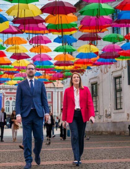 Dominic Fritz și Roberta Metsola pe o stradă cu umbrele colorate