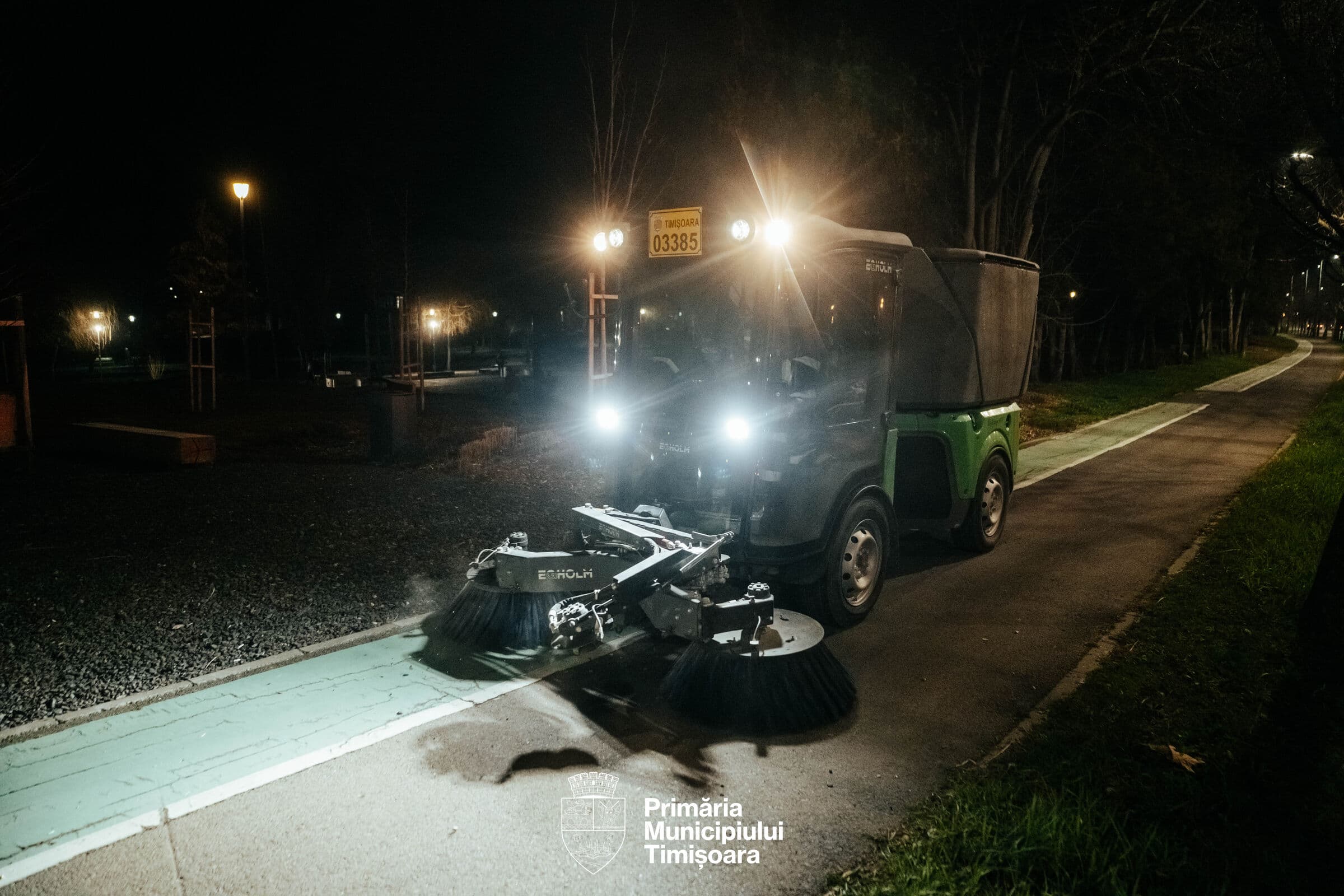 Mașină de măturat curățând noaptea o pistă de biciclete dintr-un parc din Timișoara