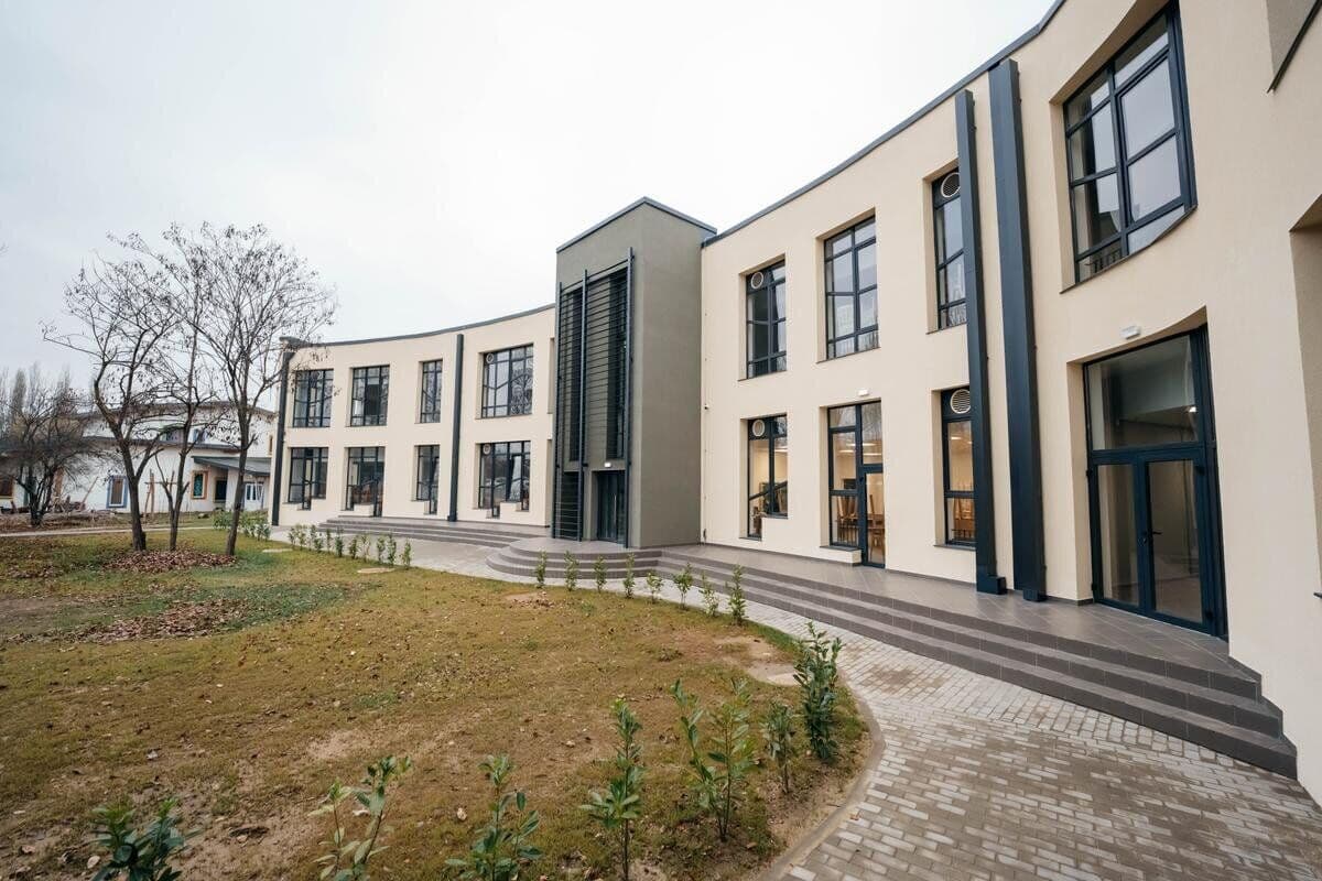 Clădire școlară nouă, curbată, cu fațadă albă și gri