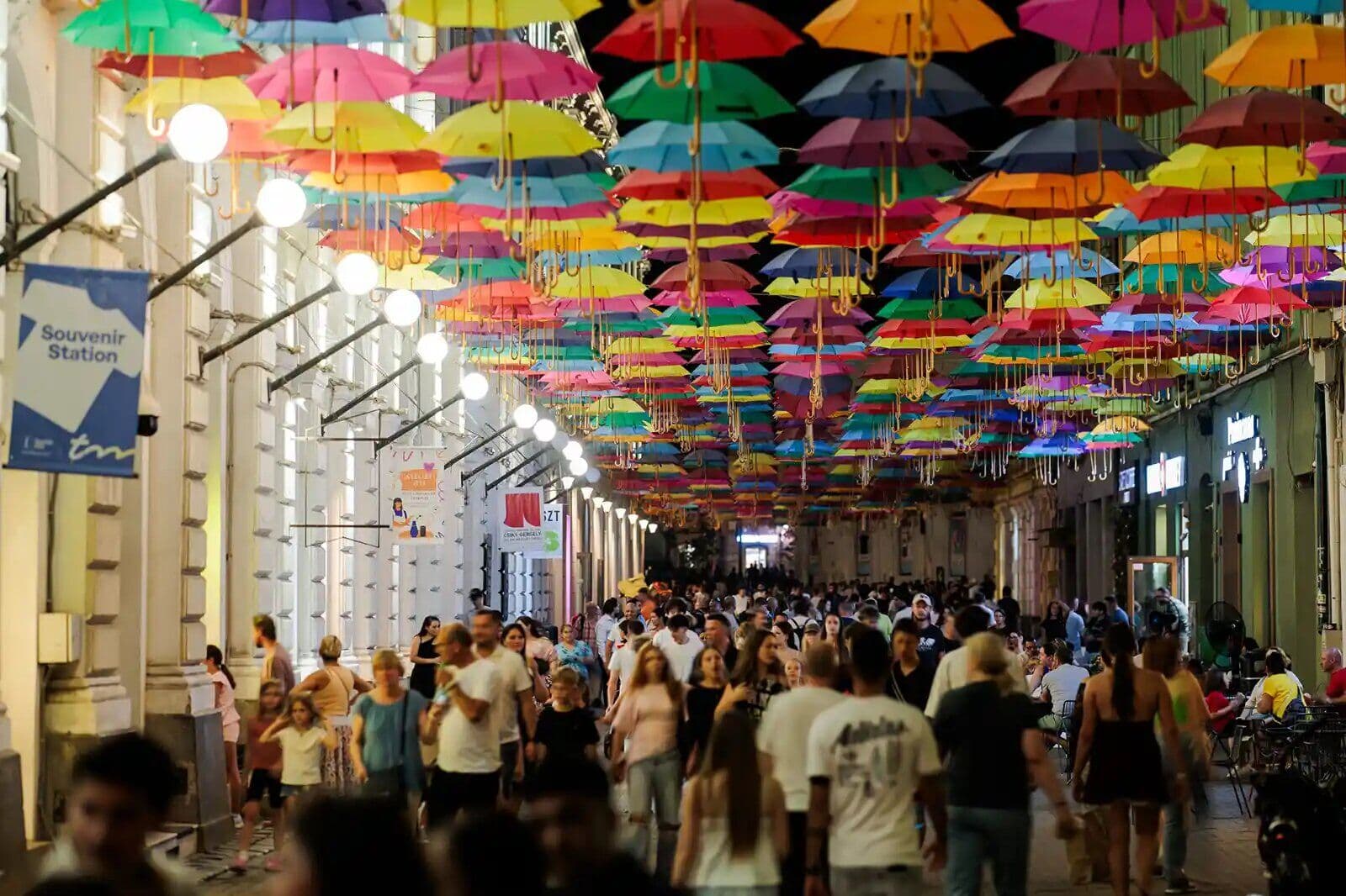 Pasaj pietonal aglomerat, cu umbrele colorate suspendate deasupra